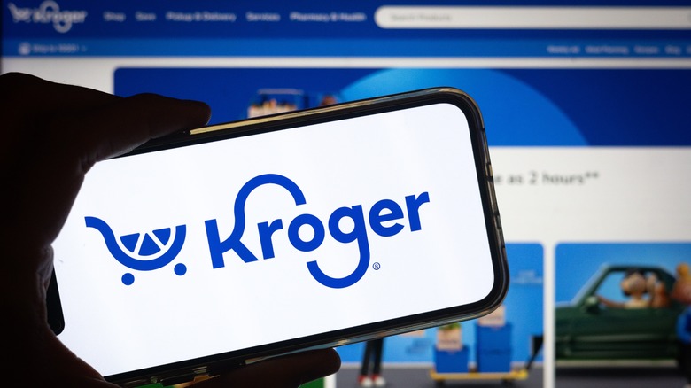 Hand holding phone with Kroger logo on screen