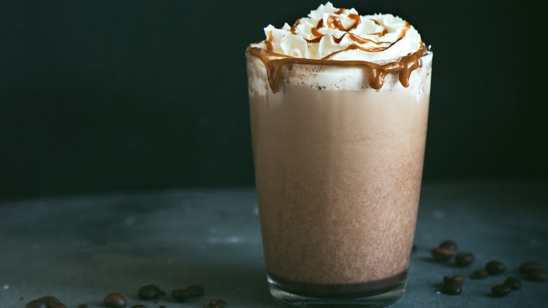 A frozen coffee in a glass with whipped cream and caramel sauce