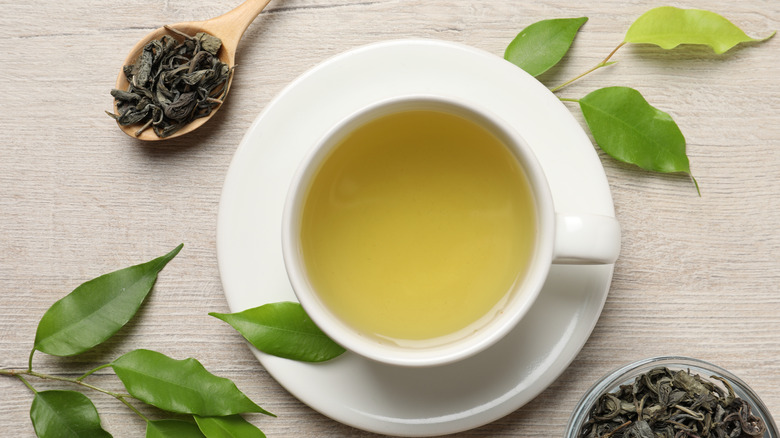 Cup of green tea and tea leaves