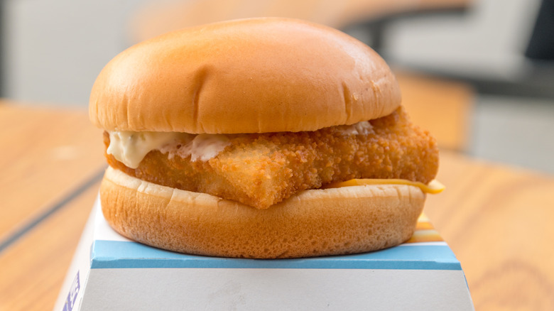 a close-up of a McDonald's Filet-O-Fish on top of the box it came in
