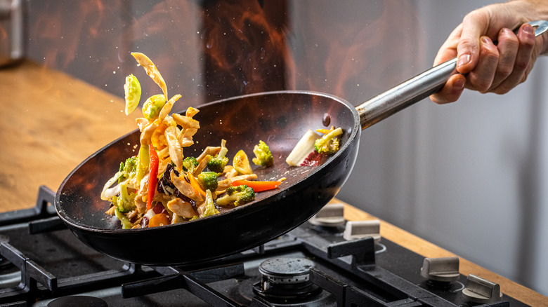 tossing stir fry in a wok