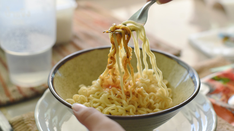 Fork getting noodles from bowl of instant ramen