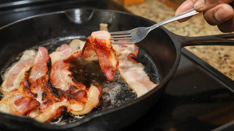 person cooking bacon in skillet