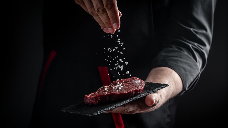 chef adding salt to steak