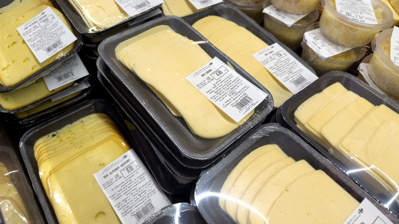 Packaged trays of sliced, white cheese in a deli