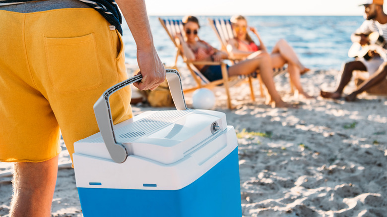 person carrying a beach cooler