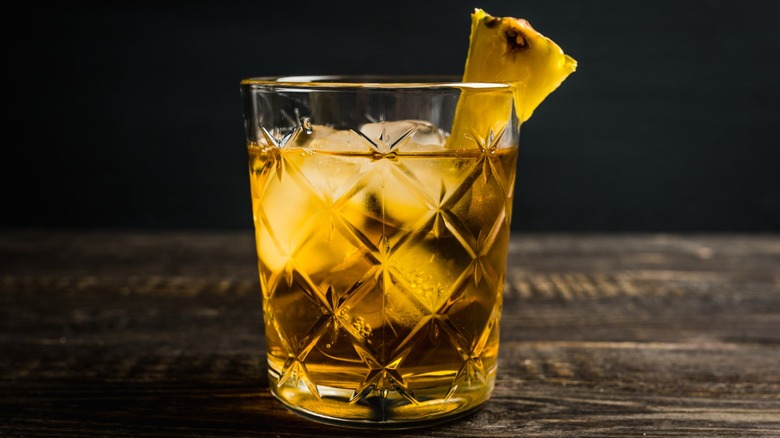 A pineapple-garnished whiskey on the rocks