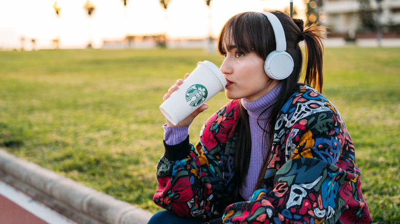 Woman with headphones drinking Starbucks