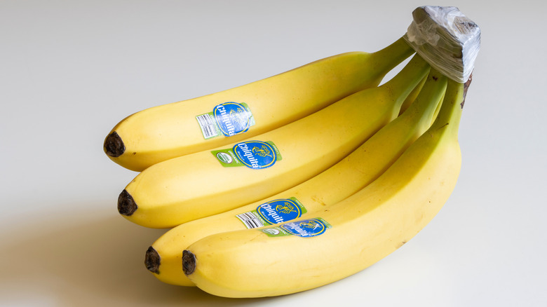 Bunch of yellow bananas with blue Chiquita stickers.