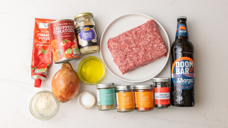 Plate of ground beef chuck, a can of chopped tomatoes, a jar of garlic paste, and other West Texas chili ingredients laid out