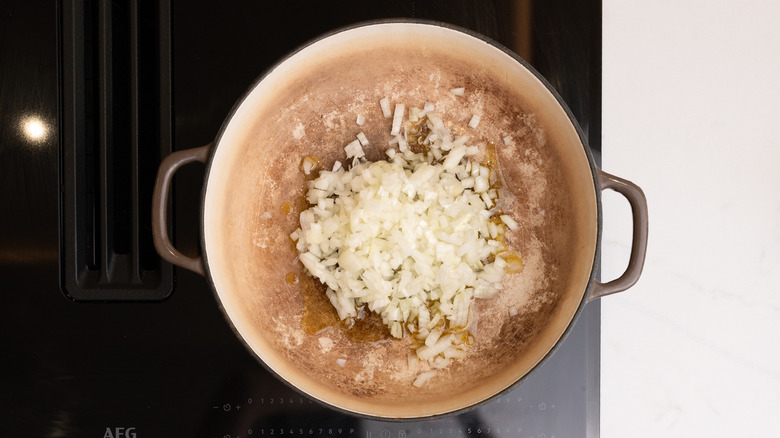 Uncooked diced onion in a pan over a stovetop