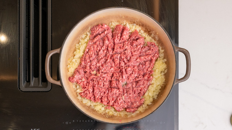 raw ground beef chuck in pan on top of diced onions