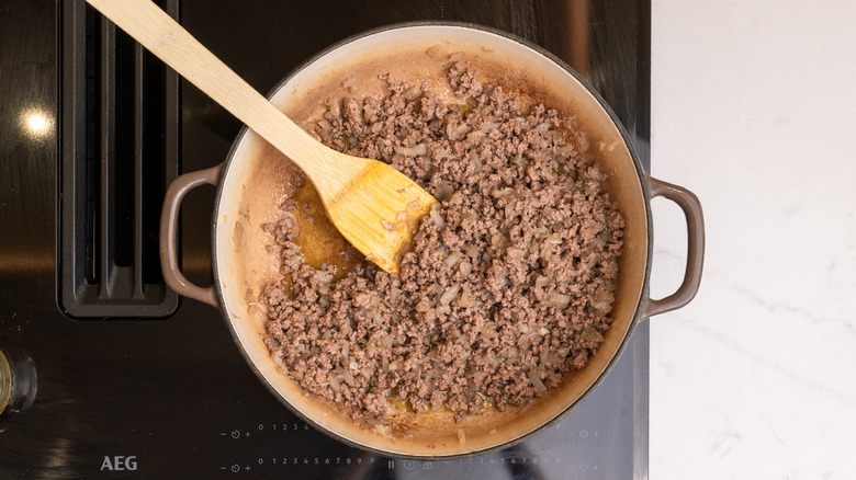 browning beef with onions in a pan on the stovetop