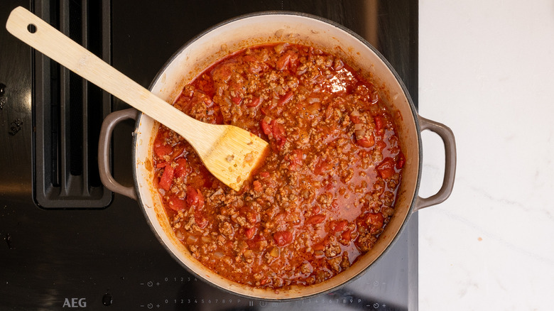West Texas chili simmering on stovetop with wooden spatula inside