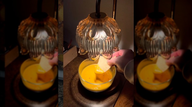 Hand dipping chip into queso bowl on candle warmer