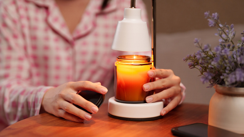 Hands placing candle onto candle warmer