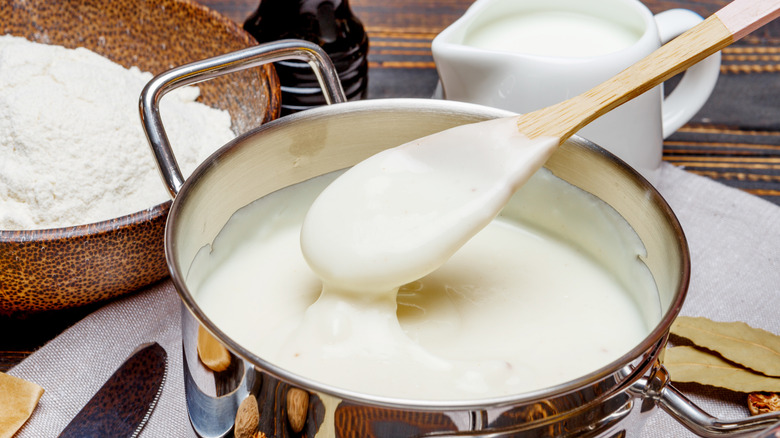 Closeup of béchamel in a saucepan with a wooden spoon