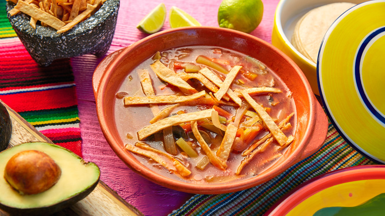 Tortilla soup with ingredients on pink board 