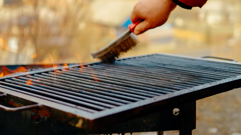 hand cleaning a grill with a grill brush