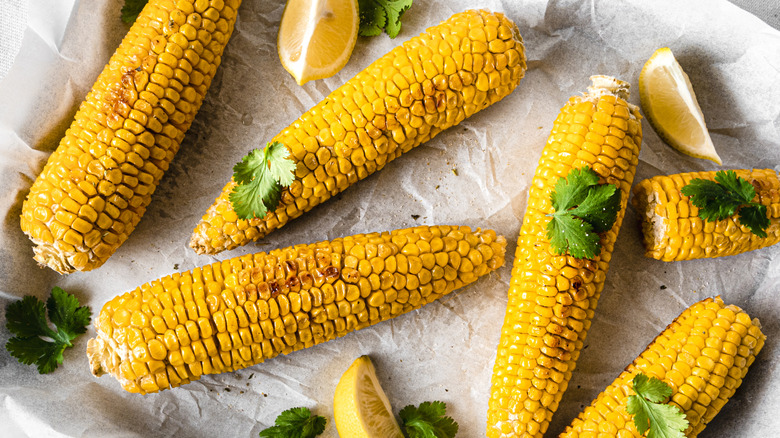 A tray of corn on the cob with parsley and lemon