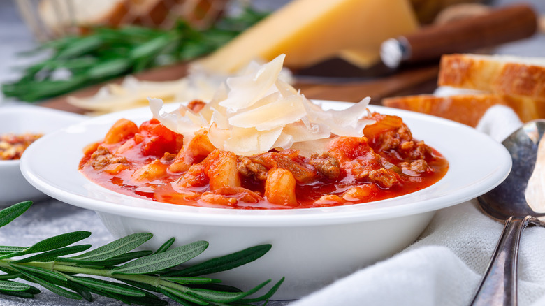 tomato based soup with parmesan on top and block in background