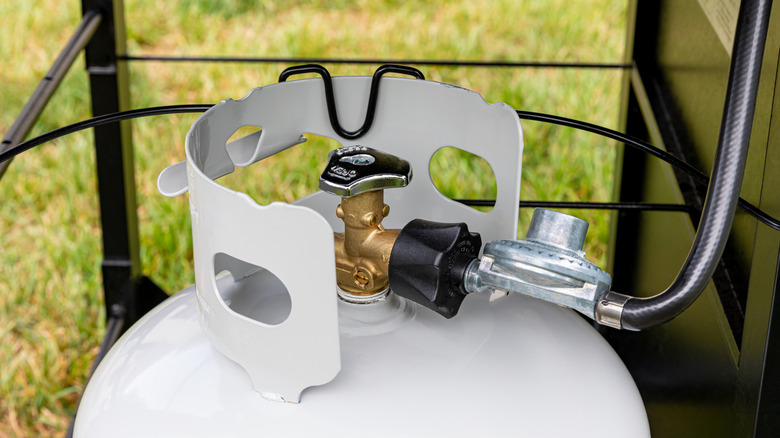 A regulator extending from a propane tank to a grill