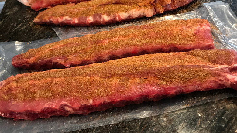 inadequate dry rub on several racks of pork ribs, barely covering sides