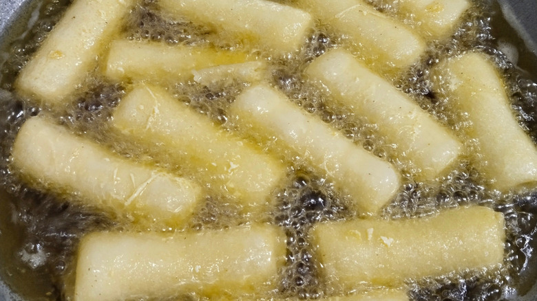 egg rolls frying in a wok of oil