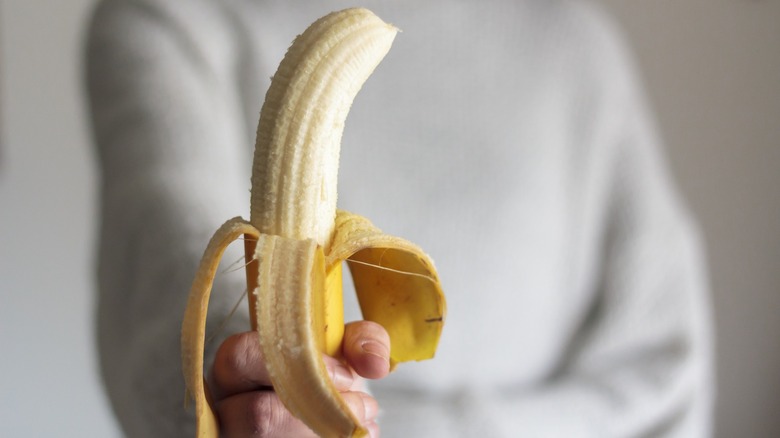 Hand holding a peeled banana