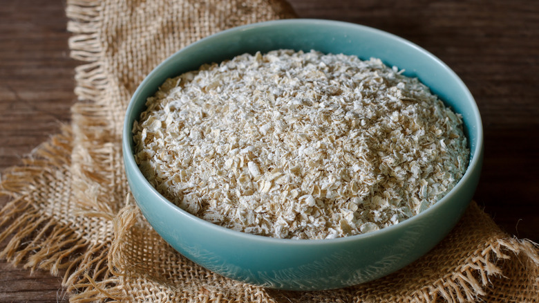Rustic image of oats in a bowl on a piece of sacking and a wooden table